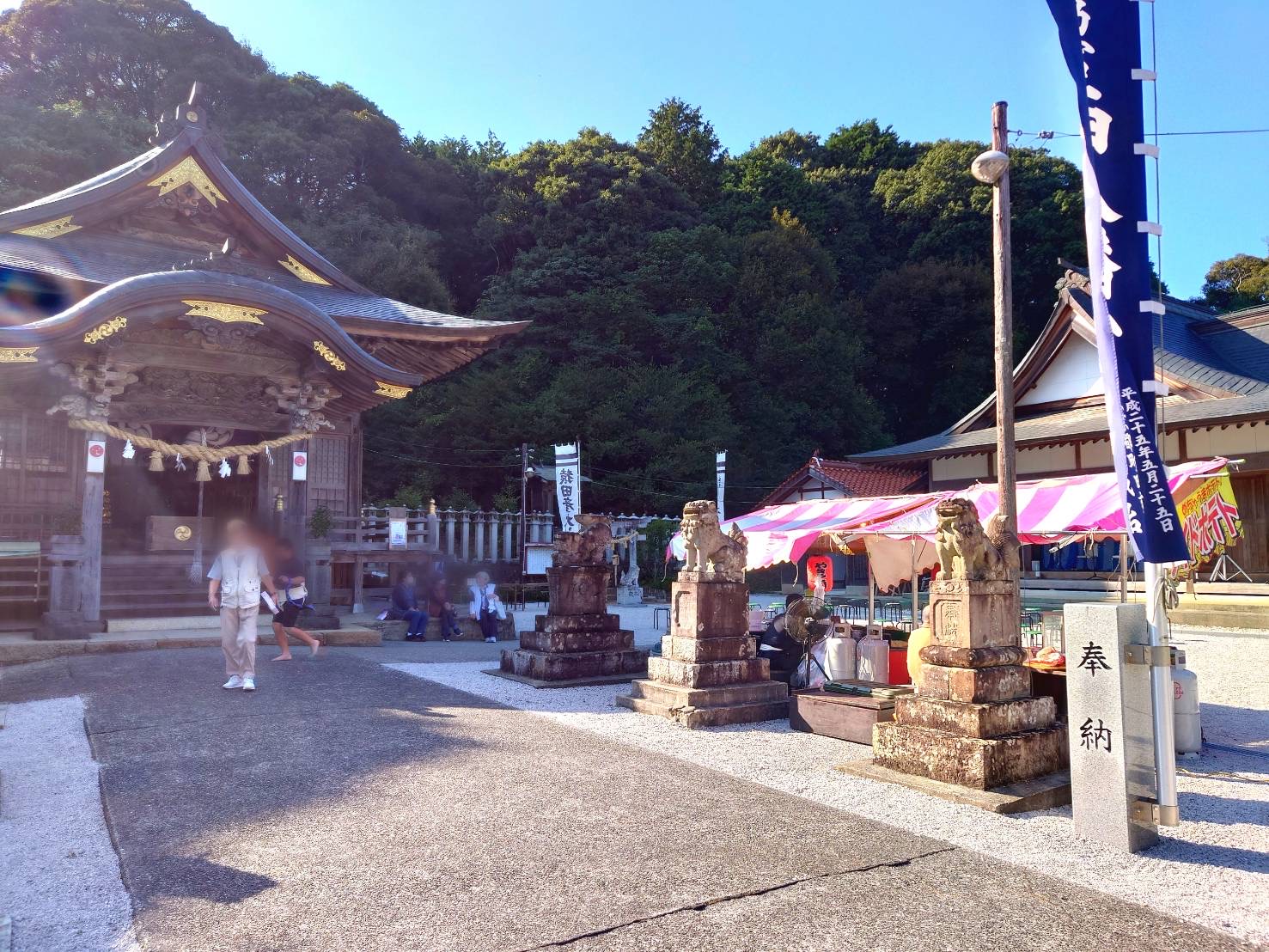 境内の様子です。拝殿の前に佇む人々と、お祭りの屋台。