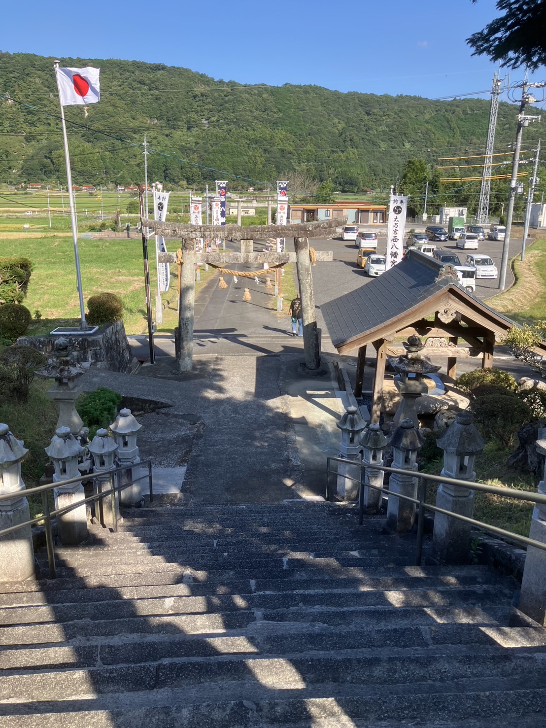 階段の上から、田んぼを横切る狭い車道を見下ろしています。ここを、軽トラが集落へ向けて出発しました。